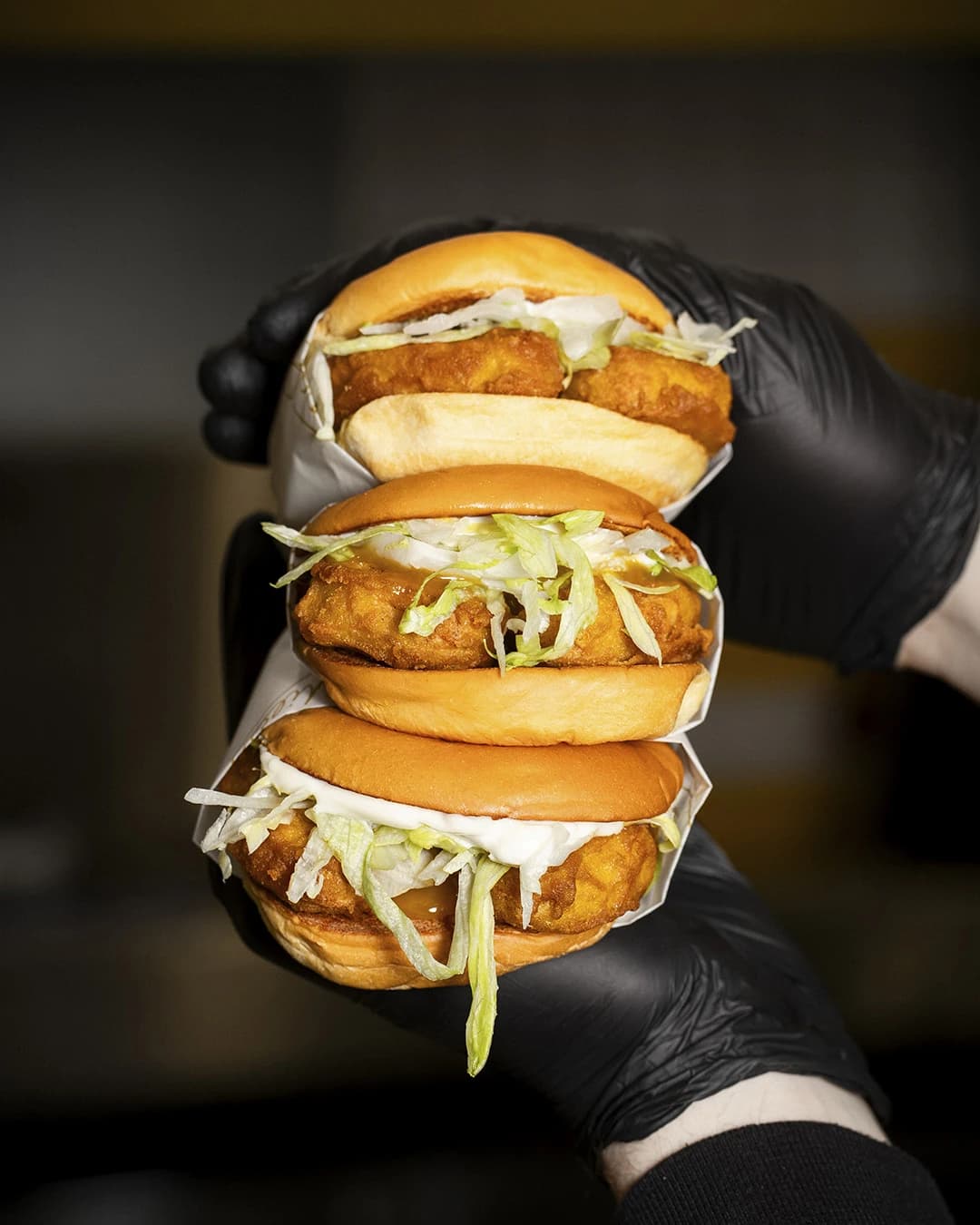 Hand im Handschuh hält zwei Goldies Chicken Burger